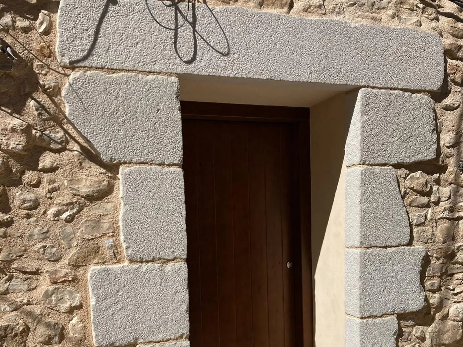 Portal amb llinda i brancals de pedra en una paret de pedra vista